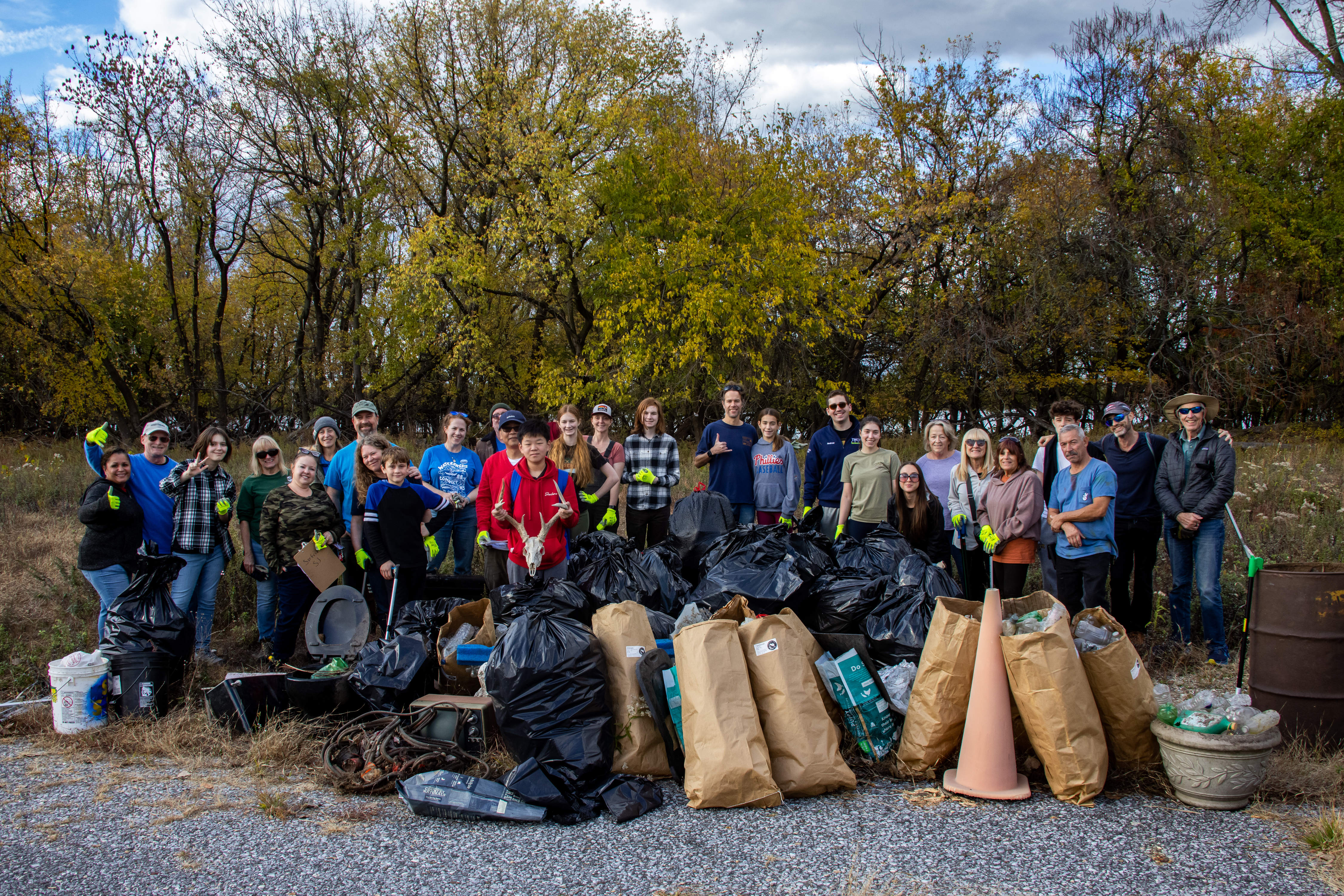 A large group of volunteers poses with trash after a clean up event